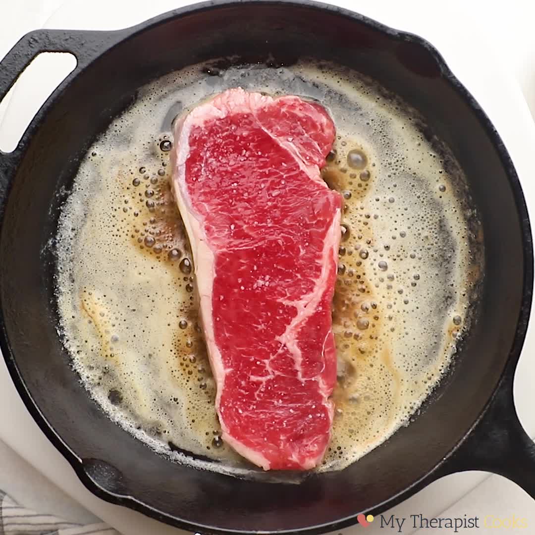 Premium Photo  Frying new york strip steak in cast iron frying pan over  the electric stove